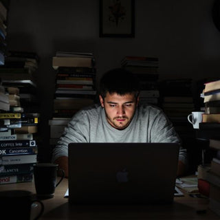 A tired student with books and coffee late at night.