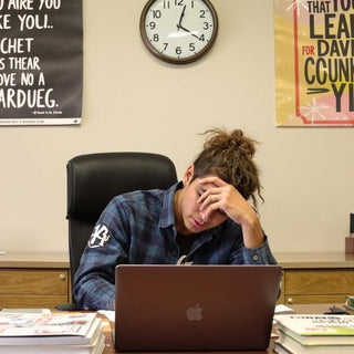 Student writing diligently at a desk with books.