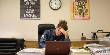 Student writing diligently at a desk with books.