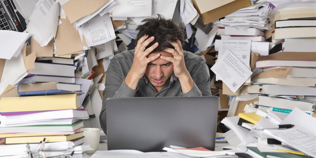 Stressed student surrounded by messy papers and textbooks.