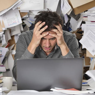 Stressed student surrounded by messy papers and textbooks.