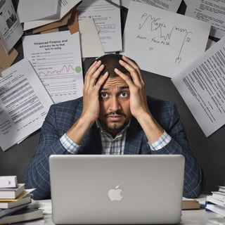 Student stressed over finance thesis with books and laptop.