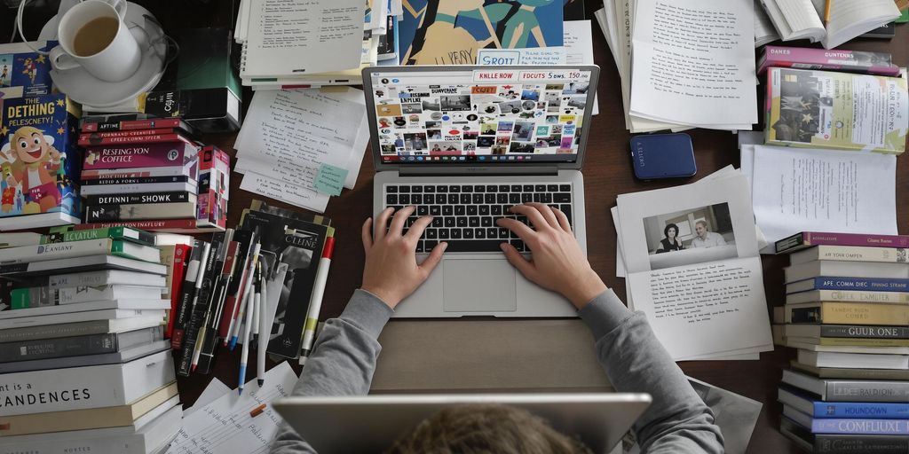 Student studying intensely at a desk full of books.