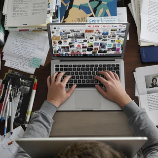 Student studying intensely at a desk full of books.