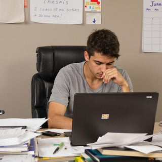 Student studying intensely at a desk full of books.