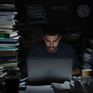 Student working late on a thesis with books and coffee.