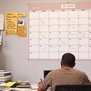 Student writing at a desk with a calendar.