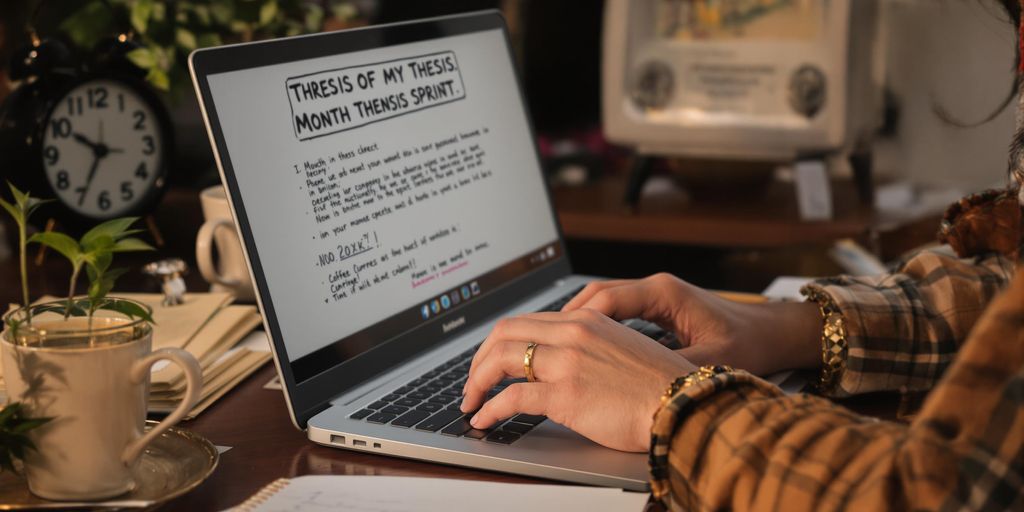 Student writing a thesis with notes and coffee.