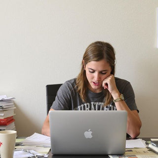 Student writing thesis at a cluttered desk.