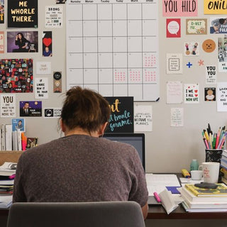 Student writing thesis at desk with books and calendar.