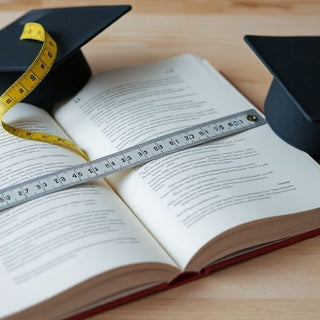 Open book, measuring tape, small academic cap.