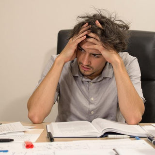 Student struggling with psychology thesis at desk.