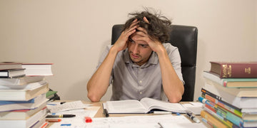 Student struggling with psychology thesis at desk.