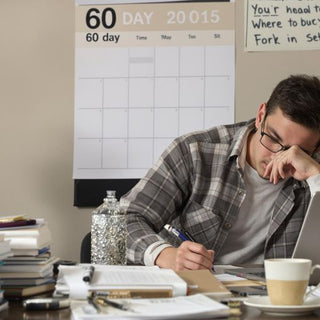 Student working diligently on thesis at cluttered desk.