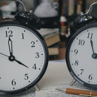 Clock, pen, books, and coffee in a study setting.