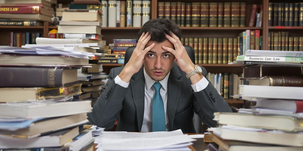 Confused student with law books in a study setting.