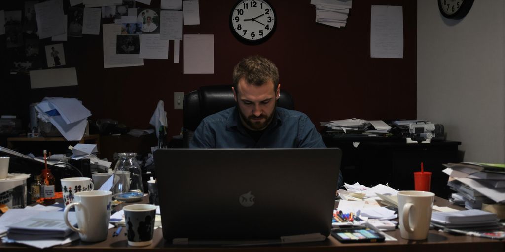 Person writing at a desk with coffee cups and papers.