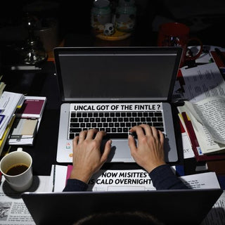 Person writing thesis at night with coffee and books.