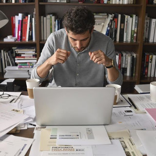 Student writing thesis with papers and coffee on desk.