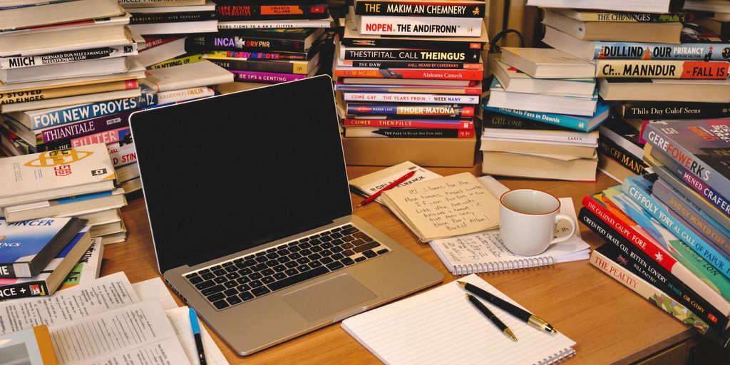 Desk setup for thesis writing with laptop and books.