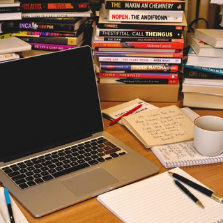 Desk setup for thesis writing with laptop and books.