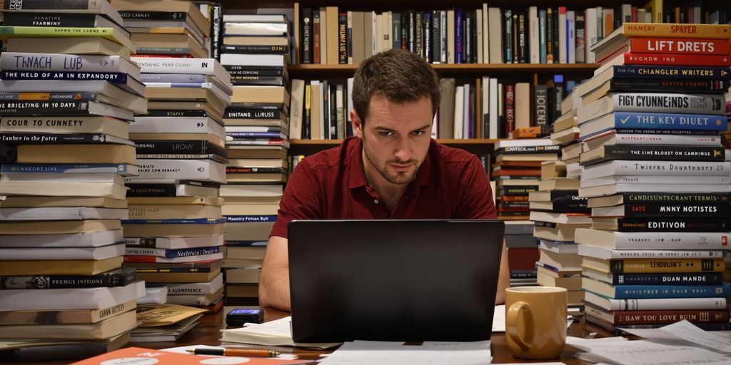 Focused writer with books and laptop in a cozy space.