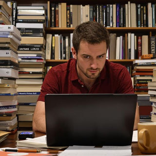 Focused writer with books and laptop in a cozy space.