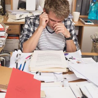 Student writing thesis at a cluttered desk.