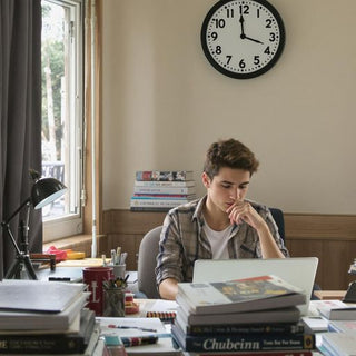 Student working diligently on thesis with a clock.